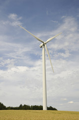 Wind turbine in a cereal field with a cloudy sky