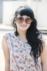 Portrait of a beautiful young Asian woman smiling confidently outdoors while wearing modern, stylish eyeglasses. Captured in natural light, the photo conveys freshness, elegance, and a casual fashion 