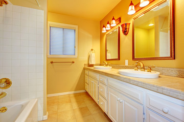 Fototapeta na wymiar Bathroom with white cabinets and gold yellow walls.
