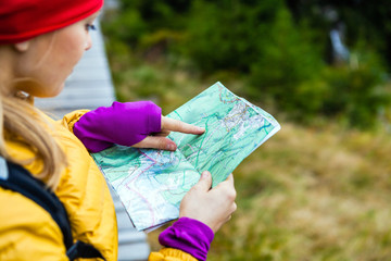 Woman hiking and reading map in forest