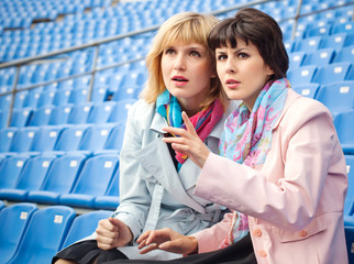 two excited  women fans watching  competition or concert in stad