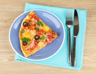 plate with a slice of delicious pizza on wooden background