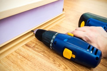 Hand holding drill. Worker lying floor panels.