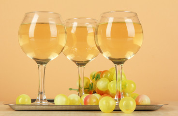 White wine in glass on salver on beige background
