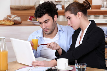 couple having breakfast and working on a laptop