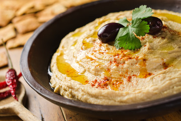 A bowl of creamy hummus with olive oil and pita chips. - 46290831