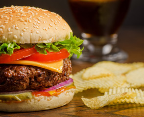 Deluxe cheeseburger with potato chips and cola.