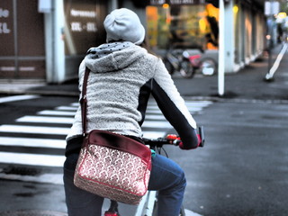 Lifestyle - Frau mit Umhängetasche fährt mit dem Fahrrad