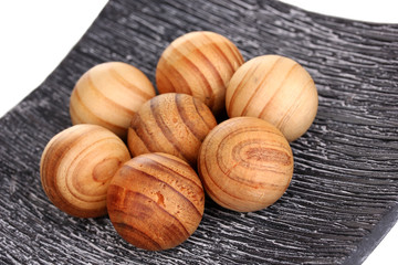 Wooden balls in decorative plate close-up.