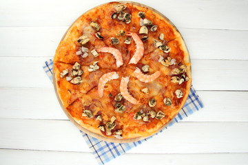 Delicious pizza with seafood on stand on wooden background