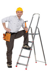 carpenter with leg resting on ladder holding hammer