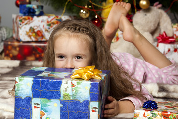 Fototapeta na wymiar The girl with a gift under the Christmas tree
