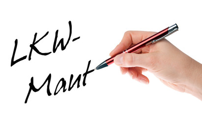 Hand mit Stift schreibt das Wort LKW-Maut