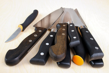 Stack of kitchen knives, wooden background
