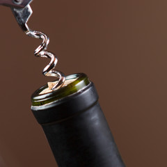 Opening of bottle of wine with corkscrew