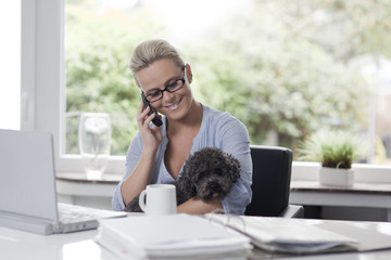 Woman working from home with a dog in her arms