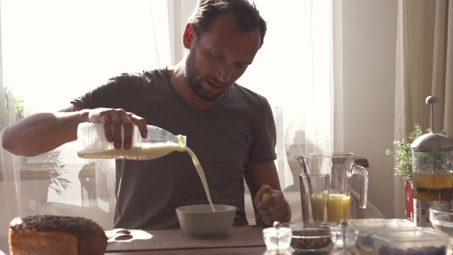 Young man pouring milk into bowl, slow motion shot at 240fps
