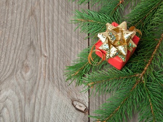 Naklejka na ściany i meble Red gift and branches a fir-tree on a wooden background 