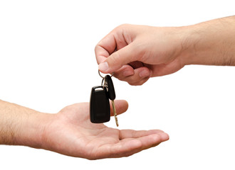 Male hand holding a car key and handing it over to another perso