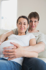 Pregnant woman lying on couch with partner