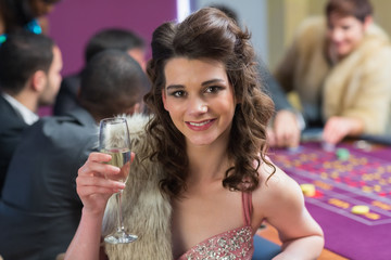 Woman smiling raising her glass at roulette table