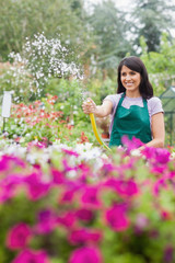 Woman having fun while watering plants with hose