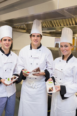 Three happy Chef's presenting cakes