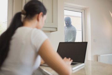Burglar looking at woman through glass door © WavebreakmediaMicro