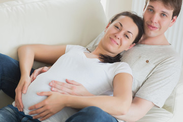 Obraz na płótnie Canvas Pregnant woman and husband lying on couch