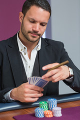Man holding a cigar looking at his cards