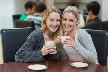 Women sitting at the coffee shop holding cups