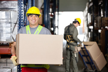 Mid Adult Foreman With Cardboard Box At Warehouse