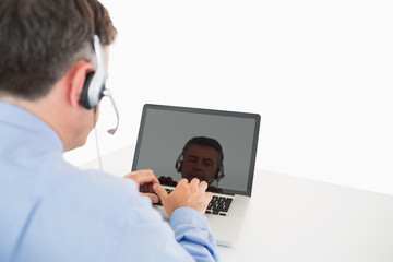 Fototapeta na wymiar Businessman with headset working on laptop