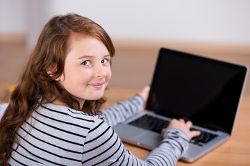 lächelndes mädchen tippt auf dem laptop