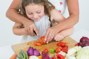 Obraz na płótnie Canvas Matka pomaga jej córka do cięcia pomidorów