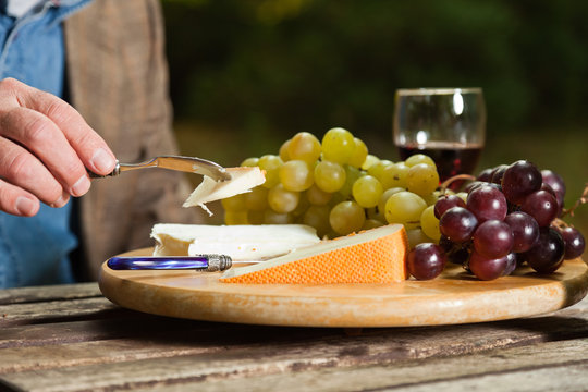 Table with plate of cheese, grapes and red wine.