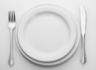 White empty plate with fork and knife isolated on white