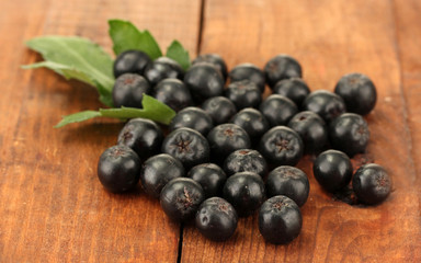 chokeberry with green leaf on wooden background close-up