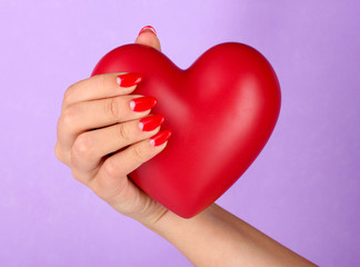 Obraz premium Red heart in woman's hand on color background