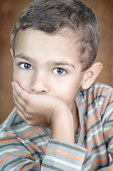 Portrait of cute litle boy covering his mouth