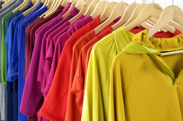 Multi colored shirts on hangers against a white background