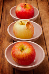 Apples in bowls on wooden table