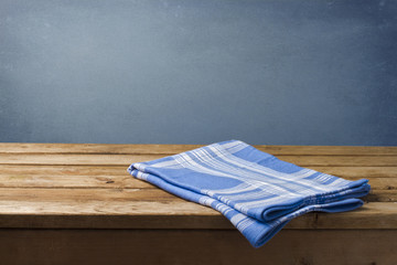 Background with wooden table, tablecloth and grunge blue wall