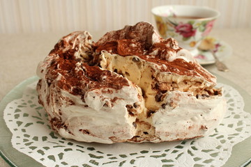Une grande meringue française avec la poudre de cacao et une tasse de thé. 