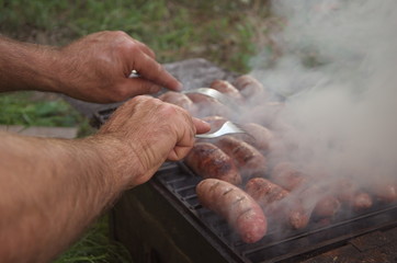 coockers hands on grilled sausages