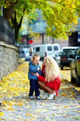 young mother talking with crying baby boy on city street