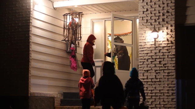 Children with family in Halloween costumes trick or treating