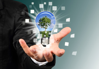 businessman hand holding a blub with tree inside