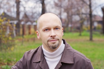 Portrait of the man of average years in autumn park