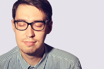 Funny young man wearing glasses with closed eyes